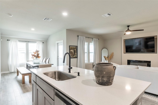 kitchen with a sink, visible vents, open floor plan, light countertops, and dishwasher