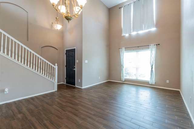 foyer entrance featuring a high ceiling, a notable chandelier, and dark hardwood / wood-style flooring