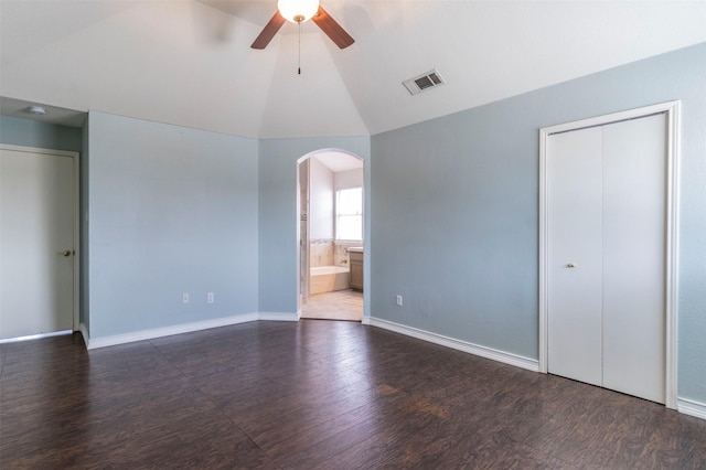 unfurnished bedroom featuring ceiling fan, vaulted ceiling, dark wood-type flooring, and ensuite bath