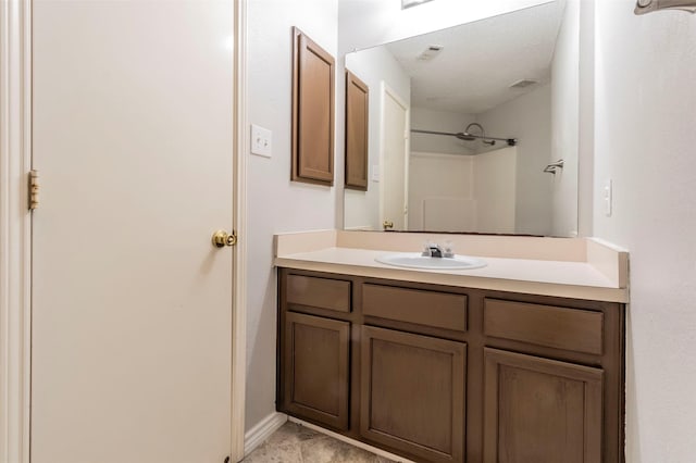 bathroom featuring a textured ceiling, vanity, and walk in shower