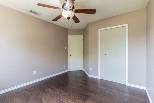 unfurnished bedroom featuring dark wood-type flooring, ceiling fan, and a closet