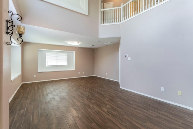 unfurnished living room with a towering ceiling and dark hardwood / wood-style floors