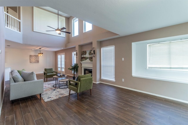 living room featuring a towering ceiling, dark hardwood / wood-style floors, ceiling fan, and a healthy amount of sunlight