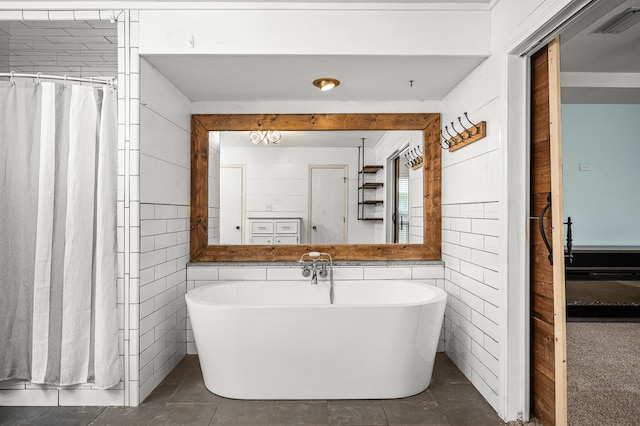 bathroom with tile walls, tile patterned flooring, and a tub