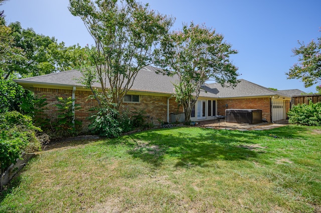 back of house with a lawn, a hot tub, a patio, and french doors