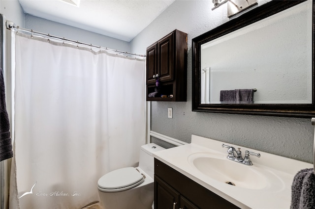 bathroom featuring vanity, a textured ceiling, and toilet