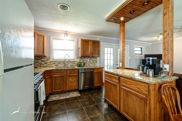 kitchen featuring appliances with stainless steel finishes, dark tile patterned floors, sink, light stone counters, and decorative backsplash