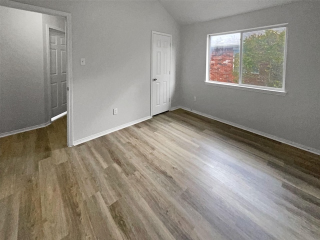 unfurnished bedroom with hardwood / wood-style floors and vaulted ceiling