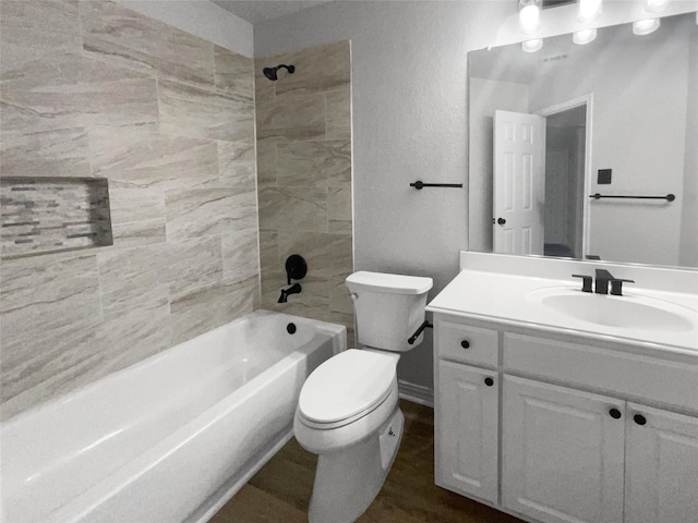 full bathroom with vanity, tiled shower / bath, toilet, and hardwood / wood-style floors