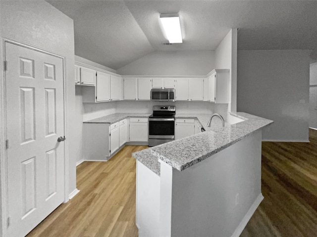 kitchen featuring appliances with stainless steel finishes, white cabinetry, kitchen peninsula, and light wood-type flooring