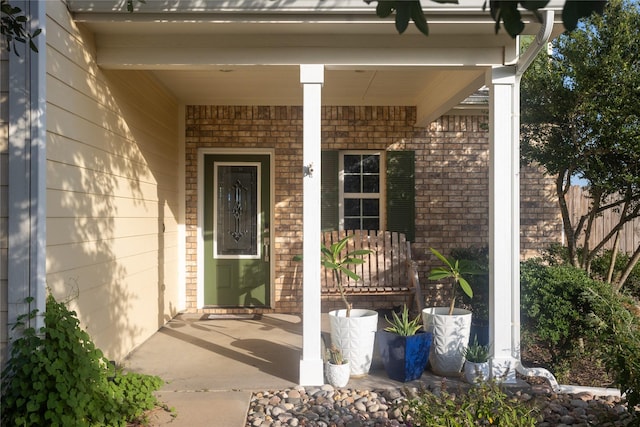 doorway to property with a porch and brick siding