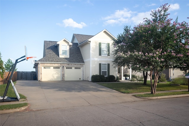 view of front of house with fence, an attached garage, a shingled roof, a front lawn, and concrete driveway