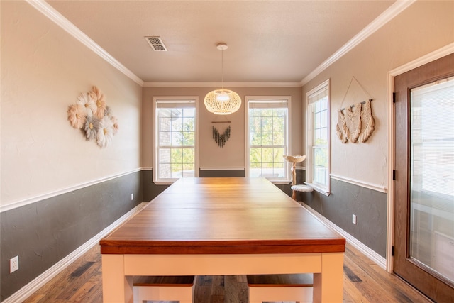 dining space with visible vents, a wainscoted wall, wood finished floors, and crown molding