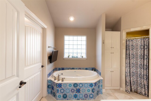 bathroom with a relaxing tiled tub and tile patterned flooring