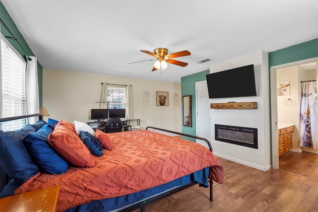 bedroom with ensuite bathroom, hardwood / wood-style flooring, and ceiling fan