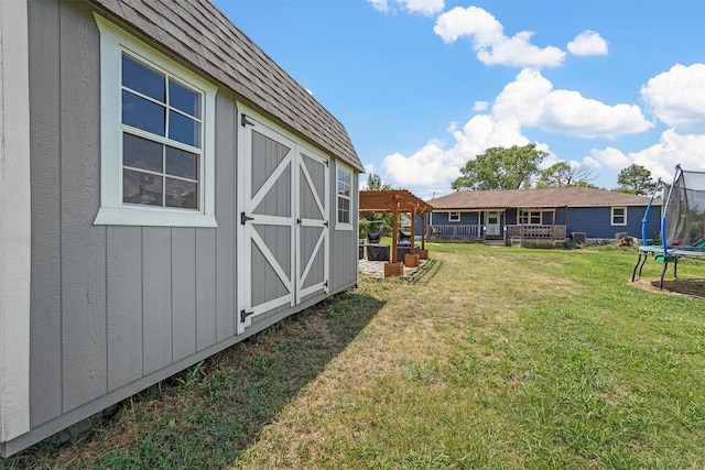 view of yard with a trampoline, a deck, and a shed