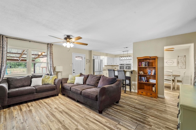 living room with a textured ceiling, wood-type flooring, and ceiling fan