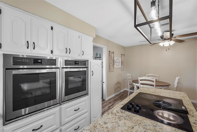 kitchen featuring white cabinets, double oven, ceiling fan, hardwood / wood-style flooring, and black cooktop