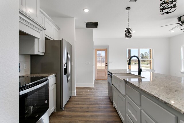 kitchen with light stone countertops, appliances with stainless steel finishes, dark hardwood / wood-style flooring, decorative backsplash, and white cabinetry