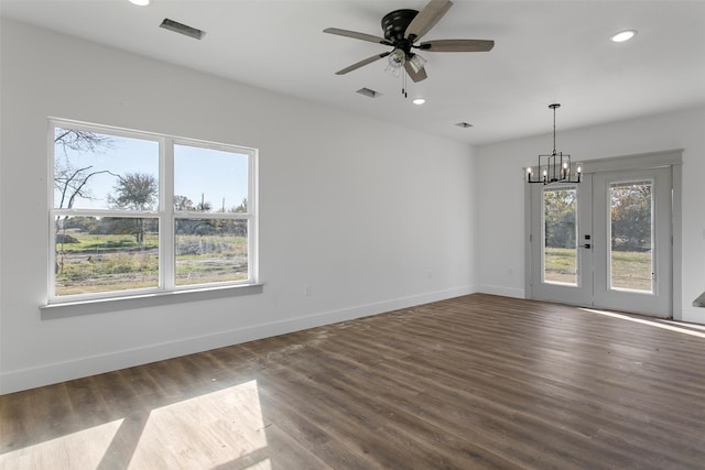 empty room with hardwood / wood-style floors, plenty of natural light, and ceiling fan with notable chandelier