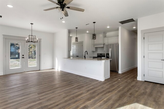 kitchen featuring kitchen peninsula, light stone counters, hanging light fixtures, and appliances with stainless steel finishes