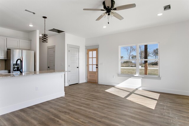 kitchen featuring stainless steel fridge, light stone counters, ceiling fan, dark wood-type flooring, and pendant lighting