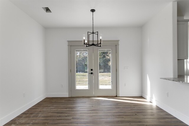 unfurnished dining area featuring dark hardwood / wood-style flooring, french doors, and an inviting chandelier