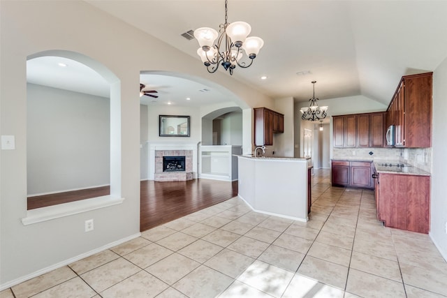 kitchen with light tile patterned flooring, lofted ceiling, ceiling fan with notable chandelier, and backsplash