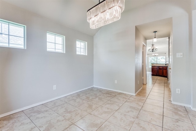 tiled spare room featuring a chandelier