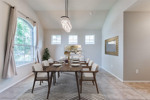 tiled dining room featuring vaulted ceiling, a healthy amount of sunlight, and an inviting chandelier