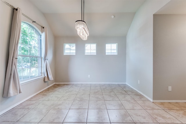 spare room featuring vaulted ceiling, plenty of natural light, and light tile patterned floors