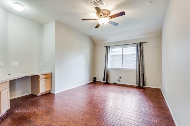 unfurnished room featuring lofted ceiling, built in desk, dark hardwood / wood-style floors, and ceiling fan