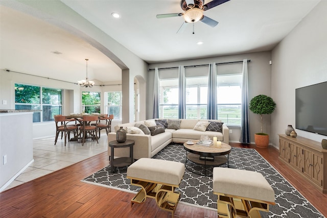 living room with ceiling fan with notable chandelier, light hardwood / wood-style flooring, and plenty of natural light