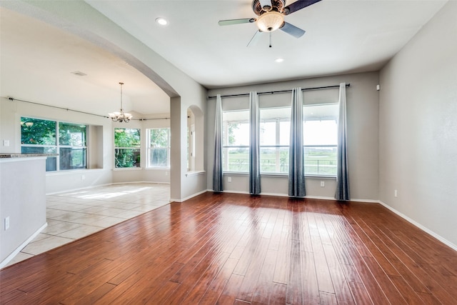 unfurnished room featuring ceiling fan with notable chandelier and light wood-type flooring