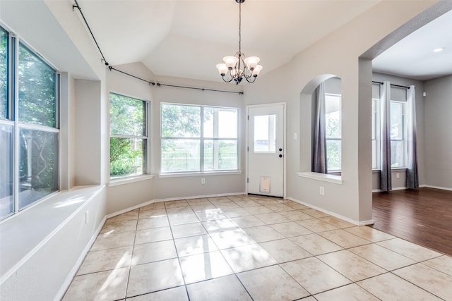 entryway with light tile patterned floors, a notable chandelier, and vaulted ceiling