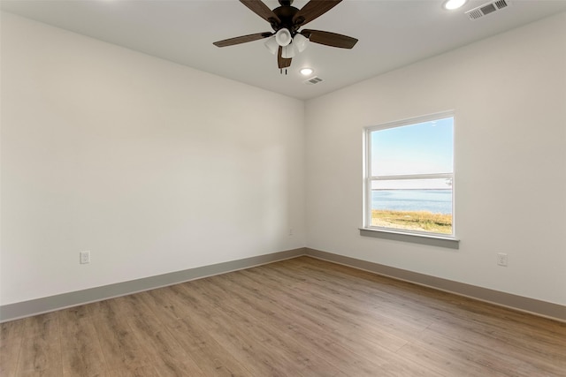 empty room with ceiling fan and light hardwood / wood-style flooring