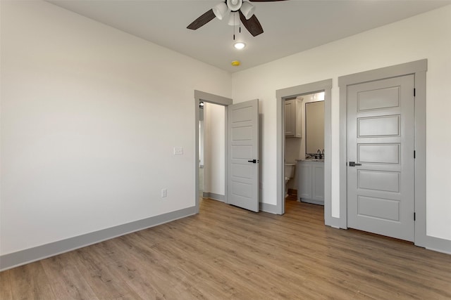 unfurnished bedroom with connected bathroom, ceiling fan, and light hardwood / wood-style flooring