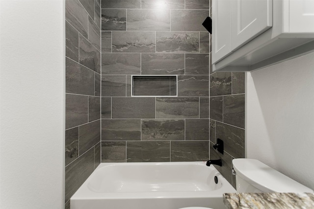 bathroom featuring toilet and tiled shower / bath