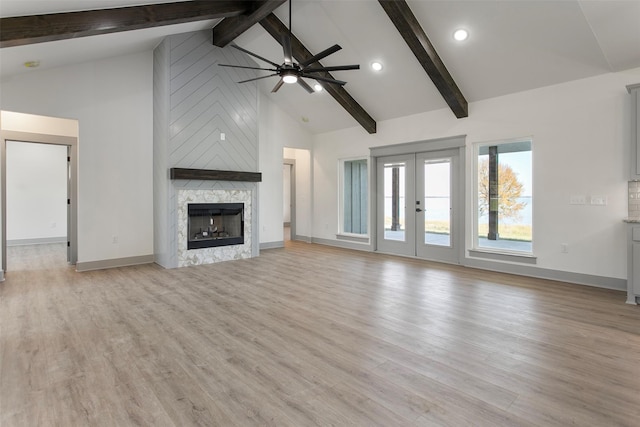 unfurnished living room featuring ceiling fan, a stone fireplace, high vaulted ceiling, and light hardwood / wood-style flooring