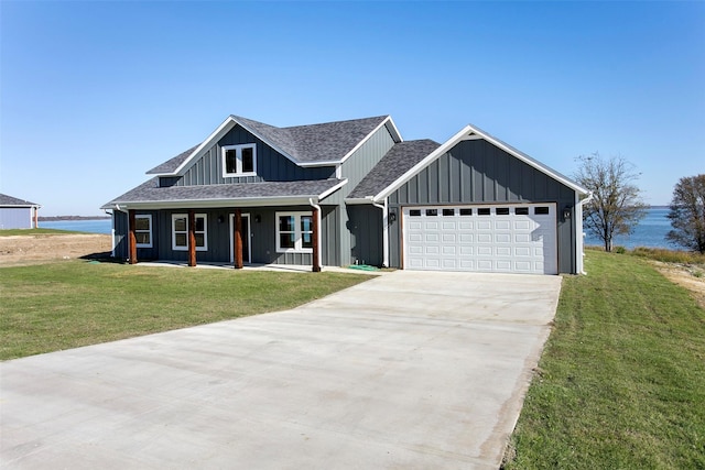 view of front facade with a porch, a water view, a front yard, and a garage