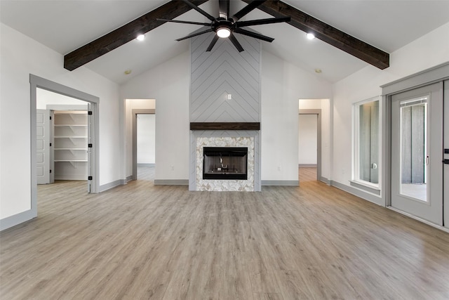 unfurnished living room featuring a stone fireplace, high vaulted ceiling, beam ceiling, and light hardwood / wood-style flooring