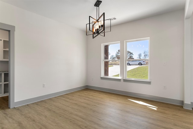 unfurnished dining area featuring a chandelier and light wood-type flooring