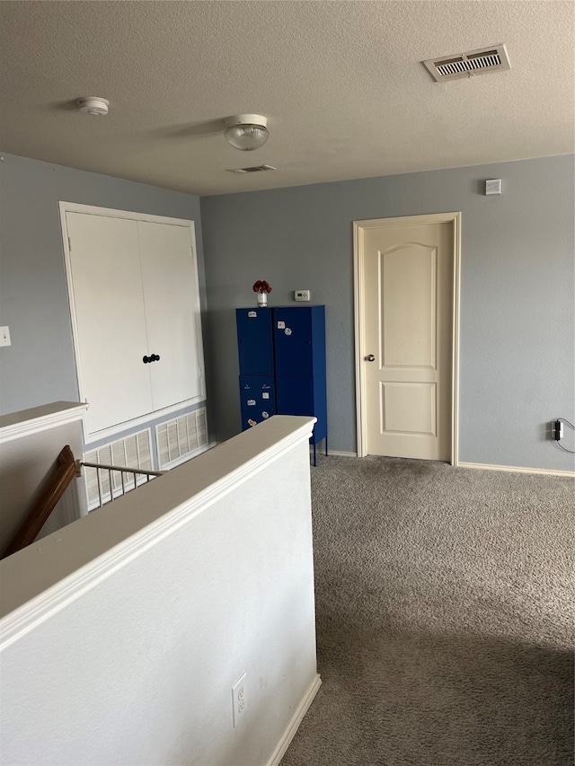 hallway featuring carpet and a textured ceiling