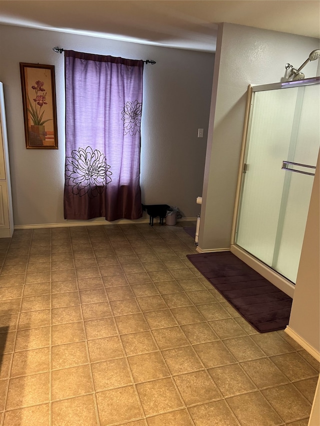 bathroom featuring a shower with door, tile patterned flooring, and toilet