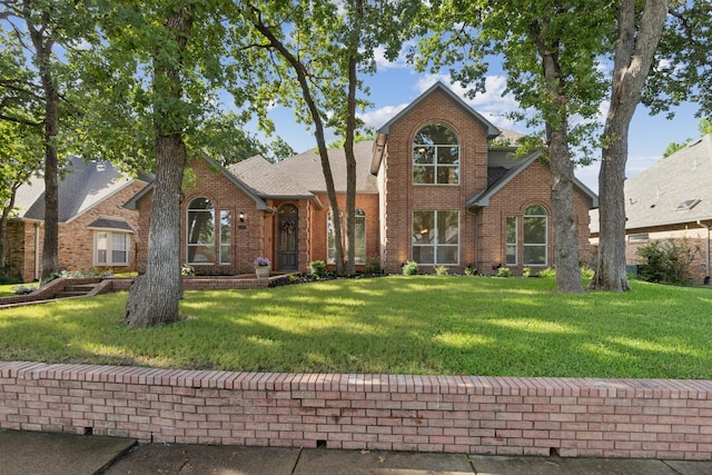 traditional-style home with brick siding, roof with shingles, and a front yard