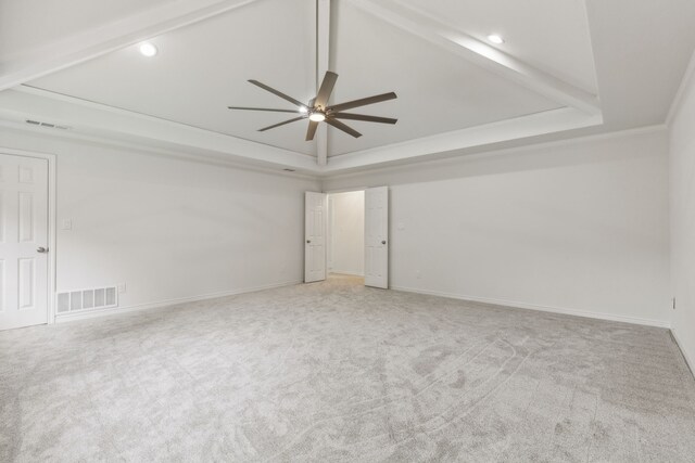 carpeted empty room featuring a raised ceiling, vaulted ceiling, crown molding, and ceiling fan