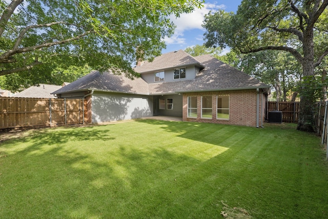 back of house featuring central air condition unit and a lawn