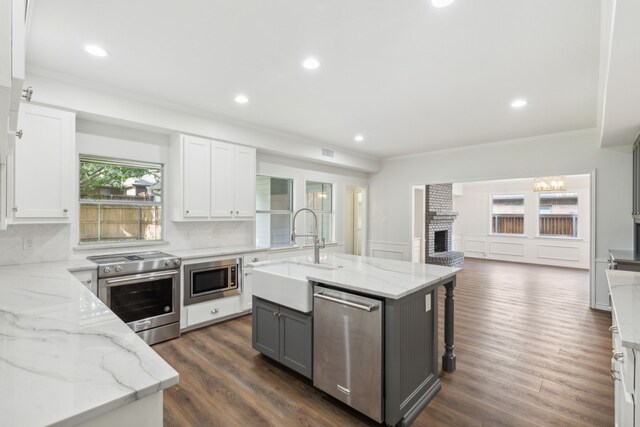 kitchen featuring backsplash, dark hardwood / wood-style floors, a brick fireplace, appliances with stainless steel finishes, and sink