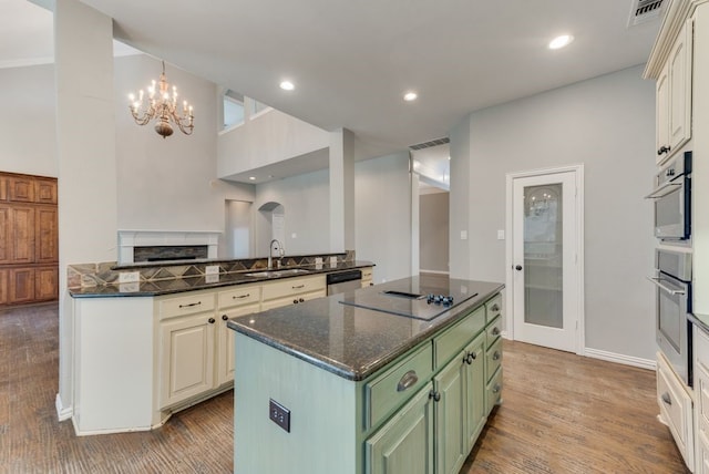 kitchen with sink, stainless steel dishwasher, green cabinets, dark stone counters, and light hardwood / wood-style floors