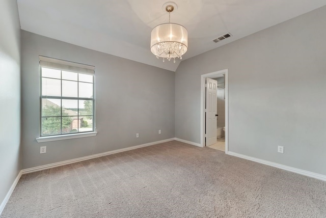 carpeted spare room with a chandelier